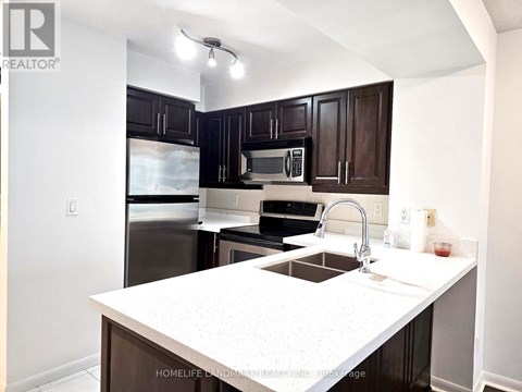 A kitchen with a white counter top and dark brown cabinets.