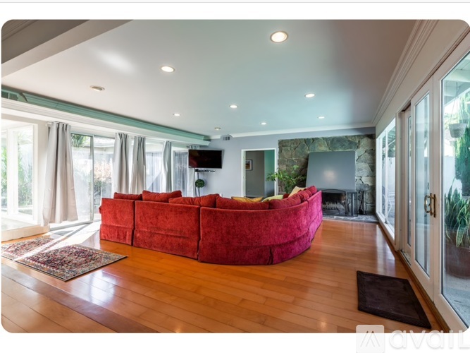 A living room with a red couch and wooden floors.