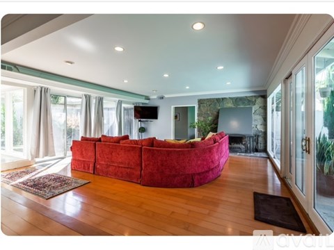 A living room with a red couch and wooden floors.