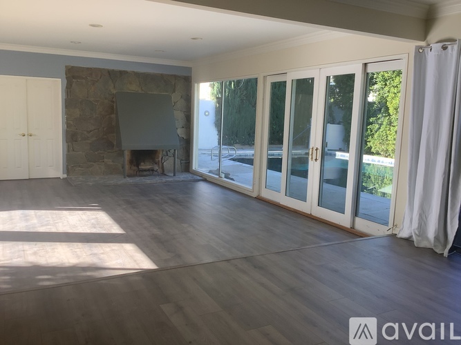 A spacious room with a stone fireplace and sliding glass doors.