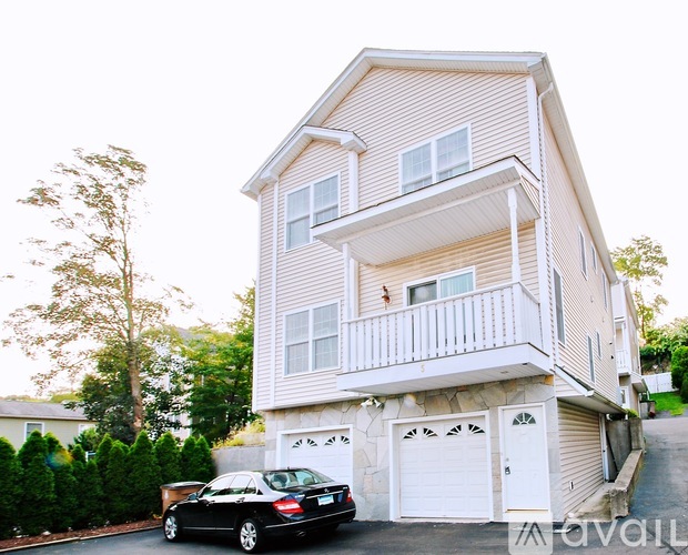 A two-story house with a balcony on the second floor and a car parked in front.