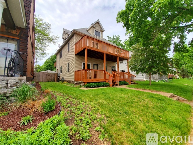 A house with a brown deck and a green lawn.