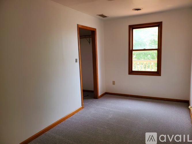 A room with a carpeted floor, a window, and a door.