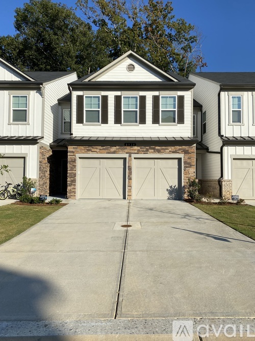 A house with a white garage door is in front of a row of houses.