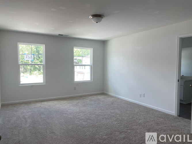 A spacious room with two windows and a carpeted floor.