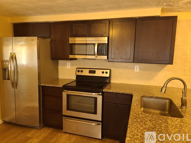 A kitchen with a stainless steel refrigerator, oven, and sink.