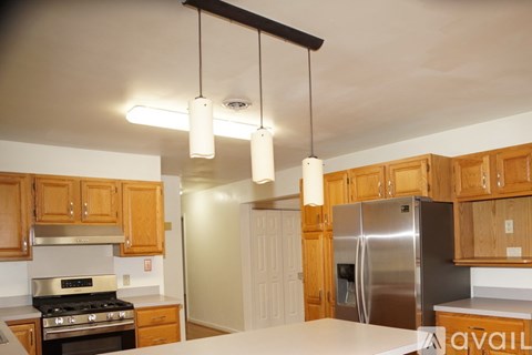 A kitchen with wooden cabinets and a stainless steel refrigerator.
