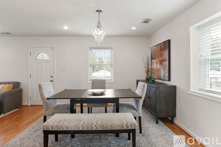 A dining room with a table set for two and a chandelier hanging from the ceiling.
