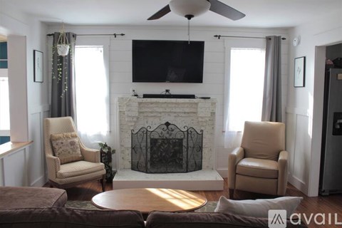 A living room with a fireplace and a television mounted above it.