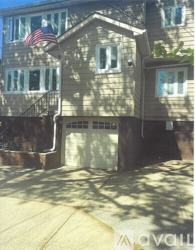 A house with a flag on the roof and a garage door.