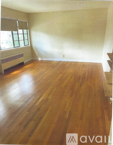 A room with wooden flooring and a window with blinds.