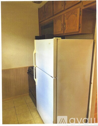 A white refrigerator in a kitchen with wooden cabinets.