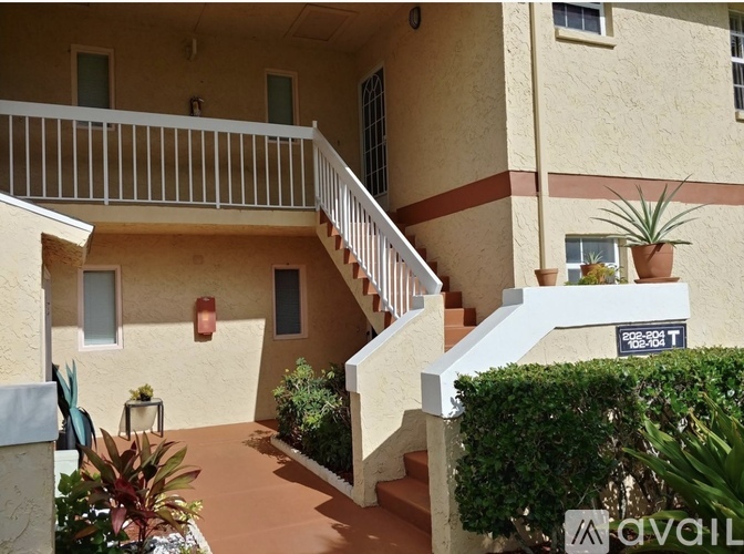 A balcony with a white railing and a staircase leading to a door.