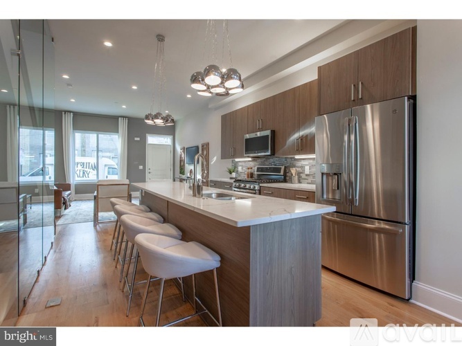 A modern kitchen with a stainless steel refrigerator and bar stools.