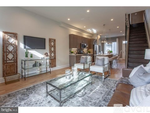 A modern living room with a glass coffee table and a staircase.