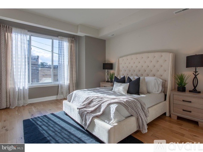 A bedroom with a large bed, a window with curtains, and a lamp on the nightstand.