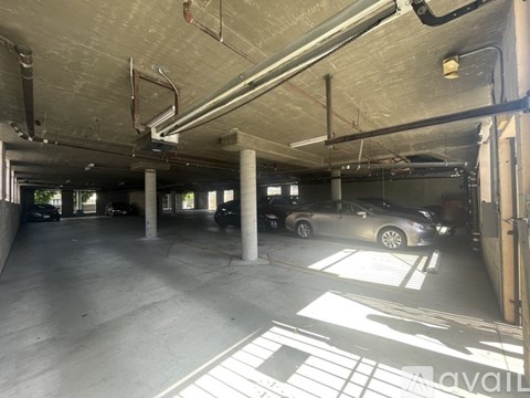 A parking garage with a few cars and a sign that says "available".