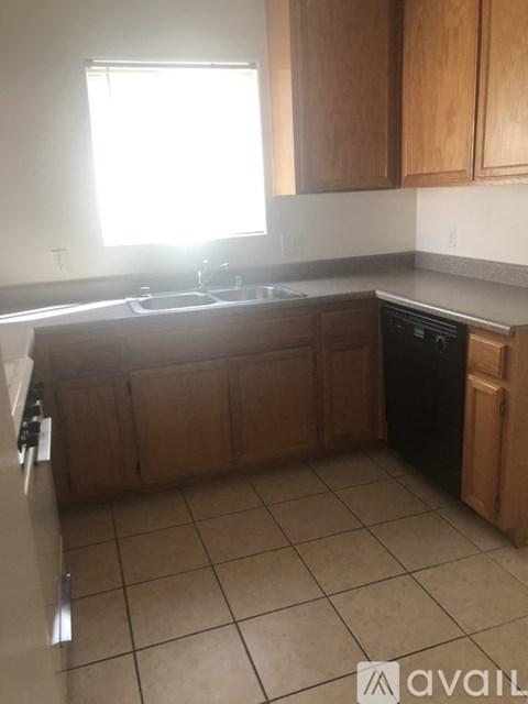 A kitchen with wooden cabinets and a black dishwasher.