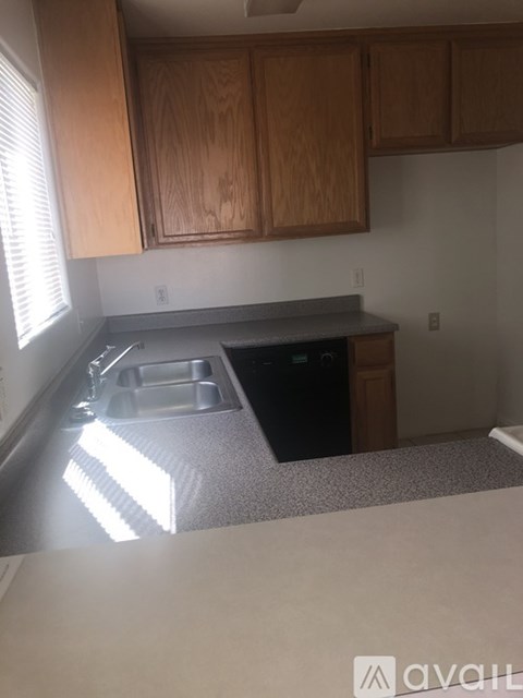 A kitchen with wooden cabinets and a black dishwasher.