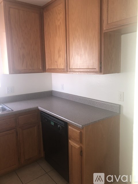 A kitchen with wooden cabinets and a black dishwasher.