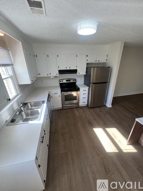 A kitchen with white cabinets and a wooden floor.
