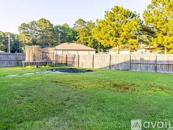 A grassy field with a fence and trees in the background.