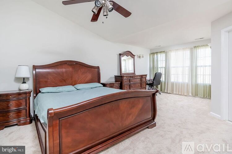 A bedroom with a large bed and a ceiling fan.