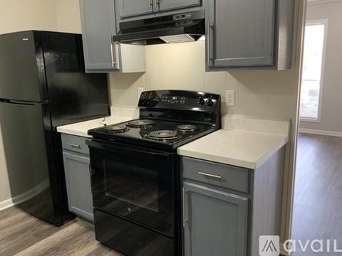 A black refrigerator is in a kitchen with a black stove and oven.