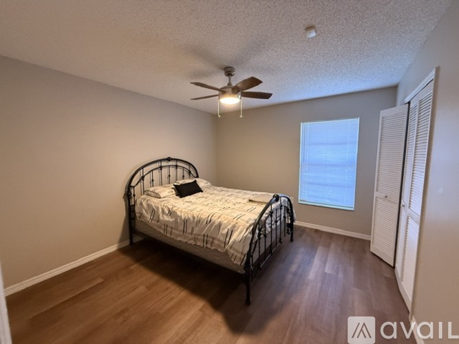 A bedroom with a bed, a ceiling fan, and a window.