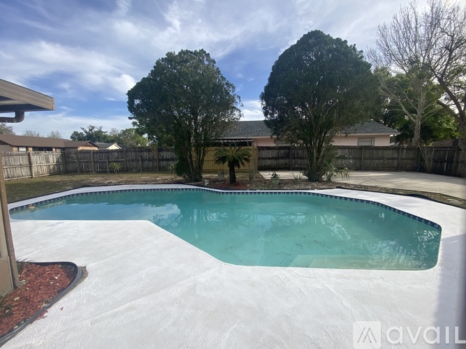 A pool surrounded by a fence and trees.
