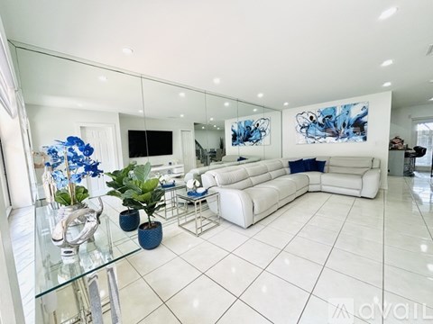 A modern living room with white furniture and a glass coffee table.