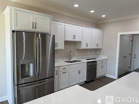 A modern kitchen with a stainless steel refrigerator and white cabinets.