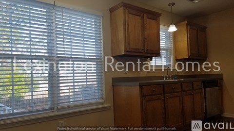A kitchen with wooden cabinets and a window with blinds.