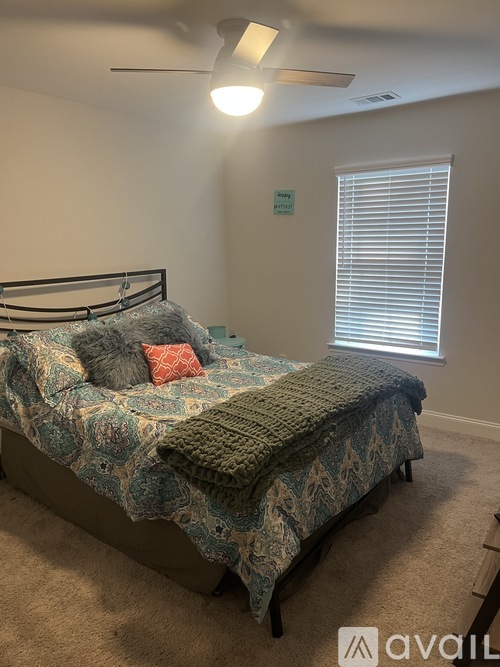A bedroom with a bed and a window with blinds.