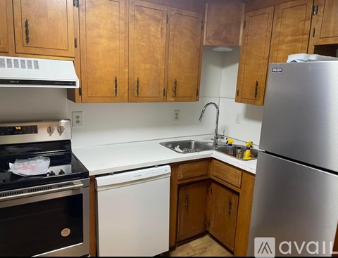 A kitchen with wooden cabinets and a stainless steel refrigerator.