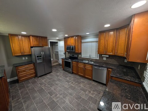 A kitchen with wooden cabinets and a black refrigerator.