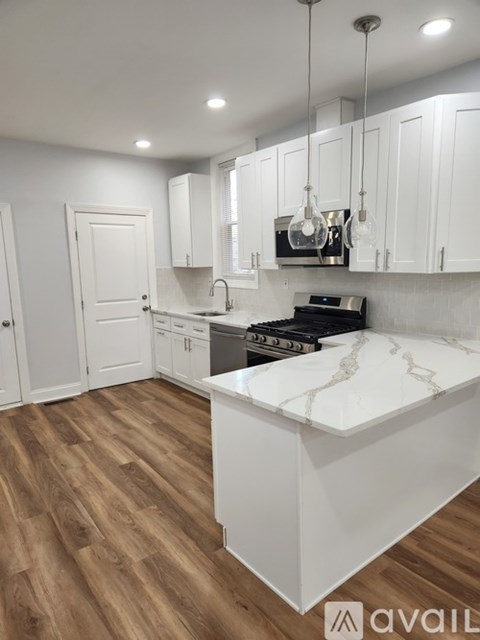 A kitchen with white cabinets and a marble countertop.