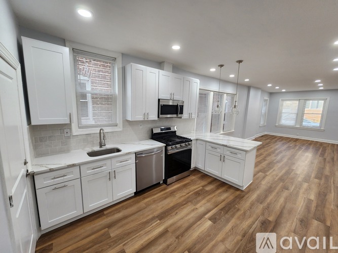 A kitchen with white cabinets and a wooden floor.