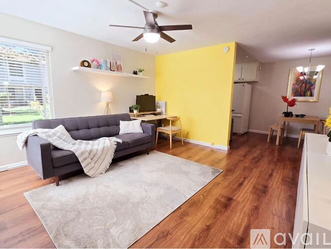 A living room with a grey couch and a grey rug.