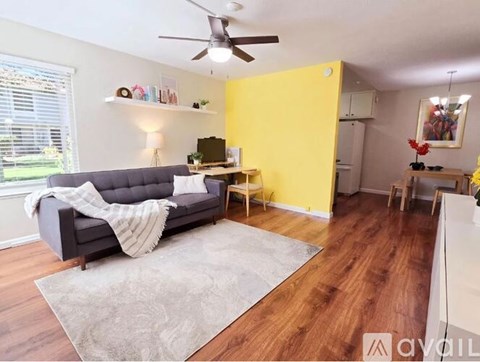 A living room with a grey couch and a grey rug.