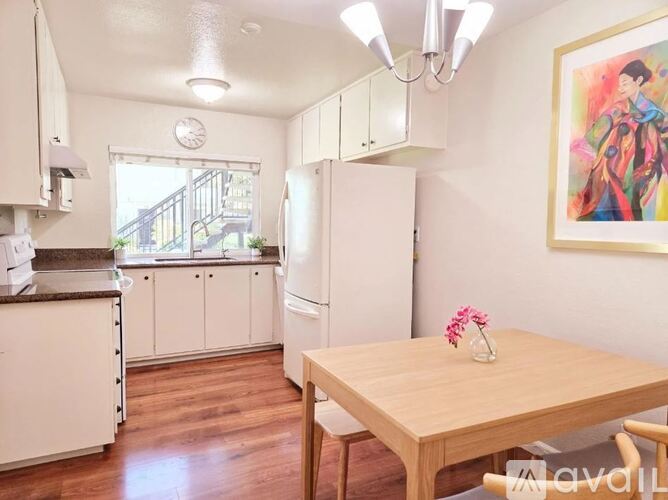 A kitchen with white cabinets and a wooden table.