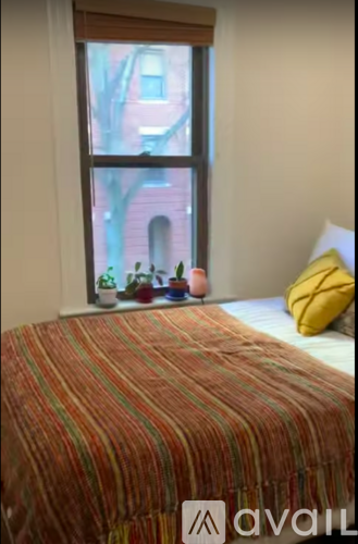 A bedroom with a bed, a window, and a yellow pillow.