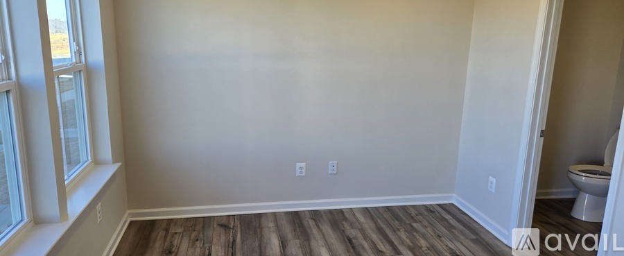 A room with wooden flooring and a window on the left side.