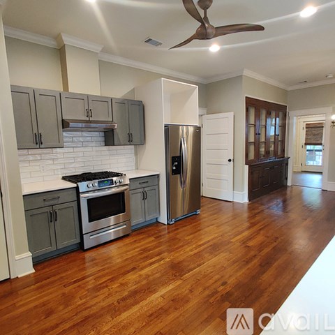 A kitchen with wooden floors and a stainless steel refrigerator.