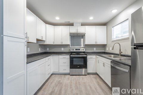 A modern kitchen with white cabinets and stainless steel appliances.