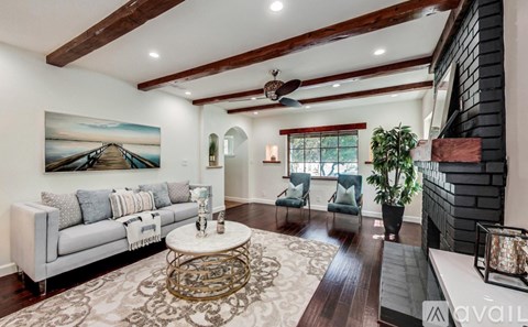 A living room with a white couch, a rug, and a painting on the wall.