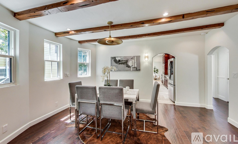 A dining room with a wooden floor and a large window.