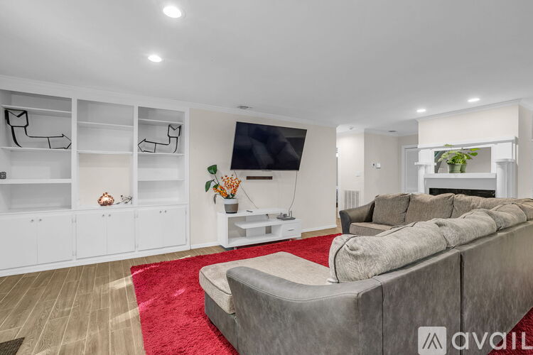 A modern living room with a grey sofa and a red rug.