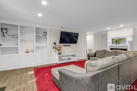 A modern living room with a grey sofa and a red rug.