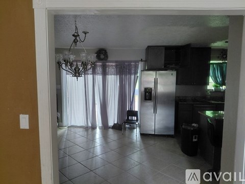A kitchen with a refrigerator, microwave, and a dining table with chairs.